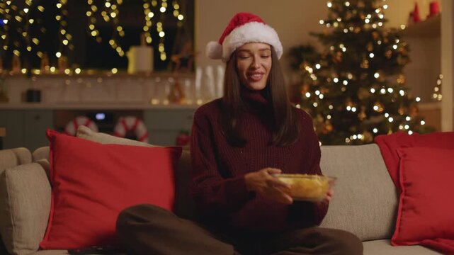 Happy woman in Santa hat watching tv at home during Christmas, 4K