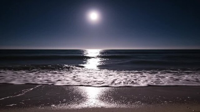 A bright moon shines over the ocean and dark beach