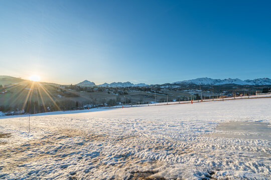 Snowy ski resort at sunrise with Tatra mountains in the background. Murzasichle village in Poland
