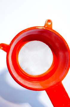 red plastic tea strainer shaped like a bear head with dual handles, isolated on a white background. Plastic Tea Strainer Kitchen Tool with Mesh Isolated on White