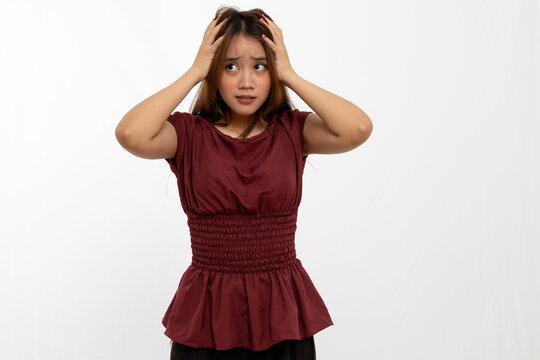 Young Woman Showing Signs of Anxiety with Hands on Head in Casual Outfit Against Neutral Background