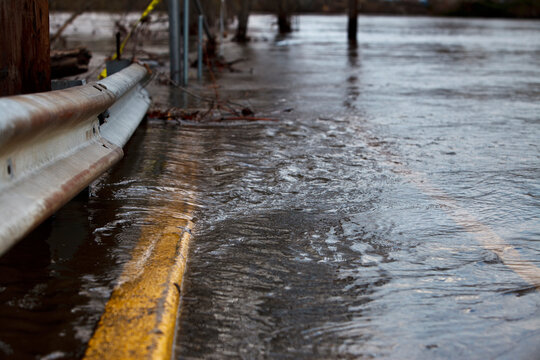 Flooded Road and Guardrail with Rushing Water Close Up Backdrop