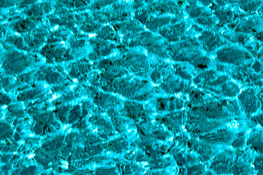 A close-up view of the detailed texture of the water in a pool or fountain, illuminated by the sun's rays