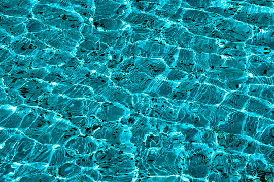 A close-up view of the detailed texture of the water in a pool or fountain, illuminated by the sun's rays