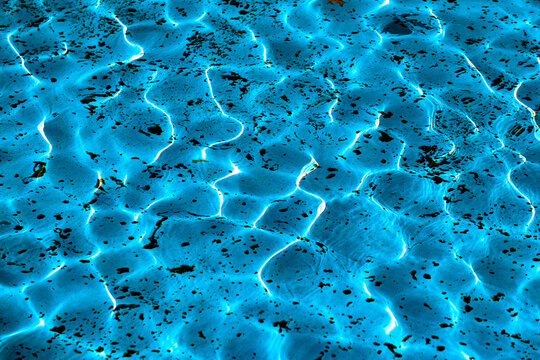 A close-up view of the detailed texture of the water in a pool or fountain, illuminated by the sun's rays