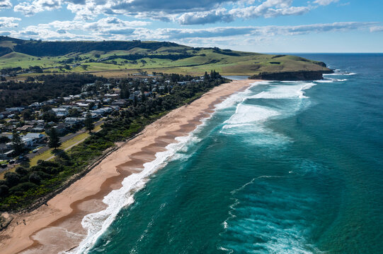 Idyllic aerial view of the beautifully scenic coastal tourist town of Gerringong and Werri surfing Beach. Captured from high above pristine turquoise blue ocean on a sunny day on the NSW South Coast.