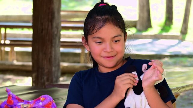 Latina girl waving, with her stuffed animal