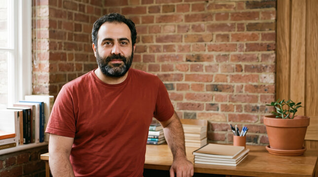 Portrait of a bearded man in a red t-shirt in a small office
