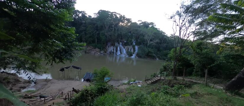 FPV drone flight over turquoise tropical waterfall in jungle, limestone canyon with crystal clear water and lush vegetation, cinematic aerial footage of pristine nature