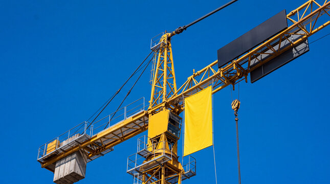Mockup Construction crane with blank yellow banner and black billboard for mockup against blue sky