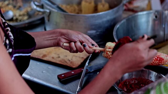Mexican street food vendor seasoning a delicious corn on the cob