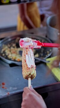 Mexican street vendor preparing traditional elote corn on the cob