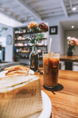 Iced coffee and layered sandwich on wooden table in cozy café, Tokyo, Japan — soft natural light, © chuangxin