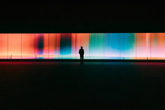Silhouette of a man standing before a massive illuminated color display screen