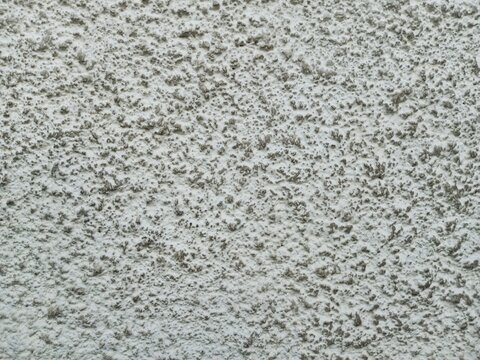 Close-up of a rough, bumpy white stucco plaster wall. A detailed exterior architectural texture background for design overlays
