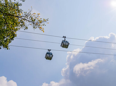 Two cable cars travel along wires under a bright blue sky.