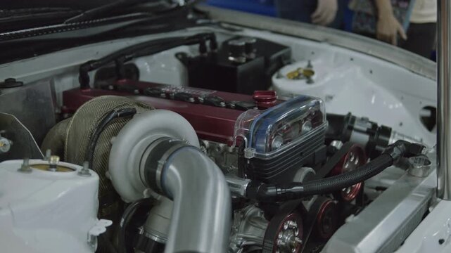 Smooth subtle panning shot across a high-performance tuned engine bay featuring a large turbocharger, custom piping, and clear cam gear cover.