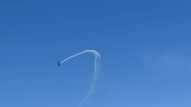 Stunt Plane Performing Aerobatic Loop with Smoke Trail in Blue Sky