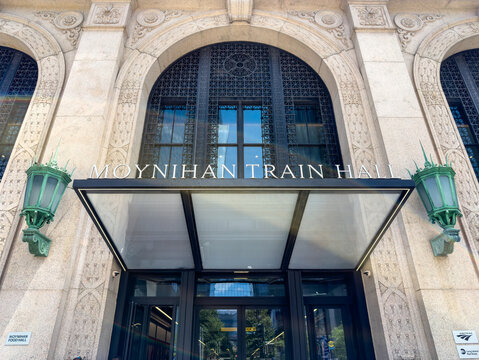Manhattan, New York, USA, July 12, 2026: The grand stone facade and modern glass canopy entrance of the Moynihan Train Hall at Penn Station, featuring its signature historic green lanterns.