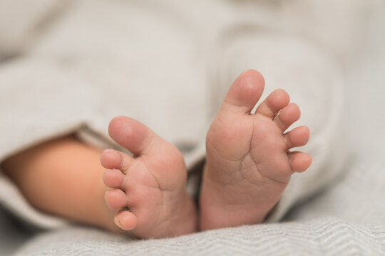 Closeup of Newborn Baby Boy feet in a cute little knitted neutral outfit on a blanket