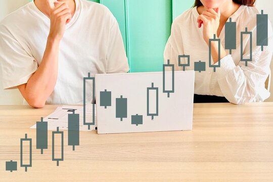 資産運用の相談をする男女と株価チャート