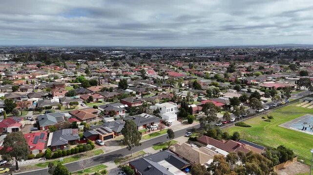 Aerial drone view contrasting established Hoppers Crossing housing with its mix of roof colours and styles against the uniform grey rooftops of newer Tarneit estates at horizon. Melbourne Australia