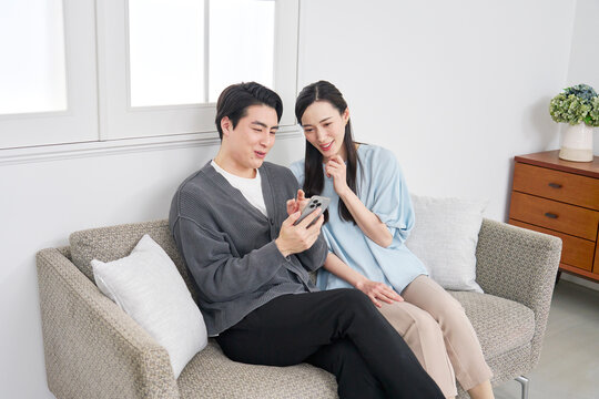 リビングでスマホを見て会話するカップル