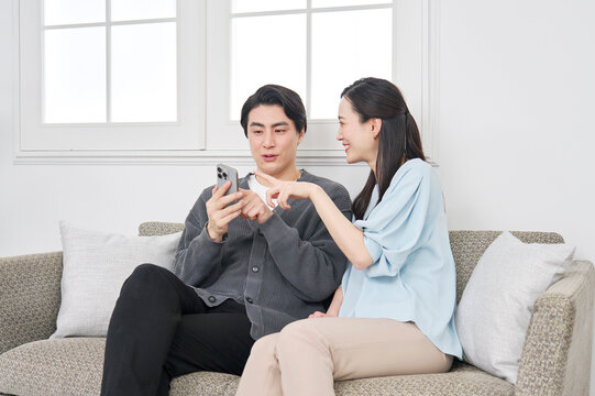 リビングでスマホを見て会話するカップル