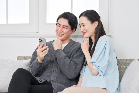 リビングでスマホを見て会話するカップル