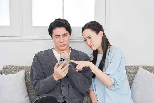 リビングでスマホを見て悩むカップル