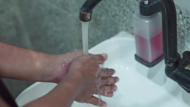 Close up of hands turning on faucet washing thoroughly under running water. Concept of higiene, cleanliness, and disease prevention