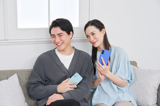 リビングでスマホを持っているカップルのポートレート　カメラ目線