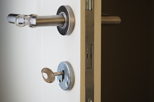 Close-up view of a door lock and key in a simple hallway setting