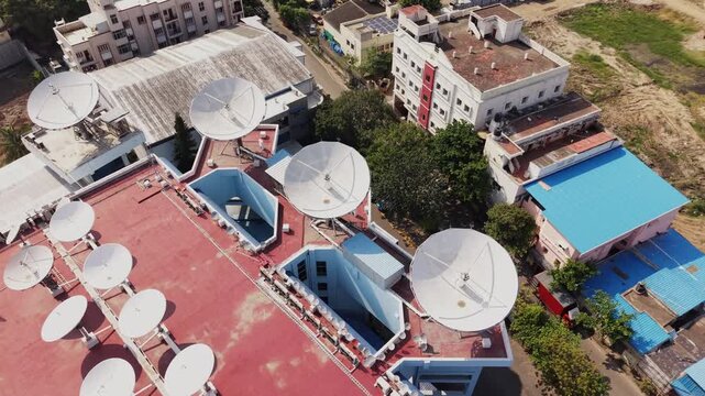 Multiple satellite dish antennas on red rooftop aerial telecommunication broadcast technology