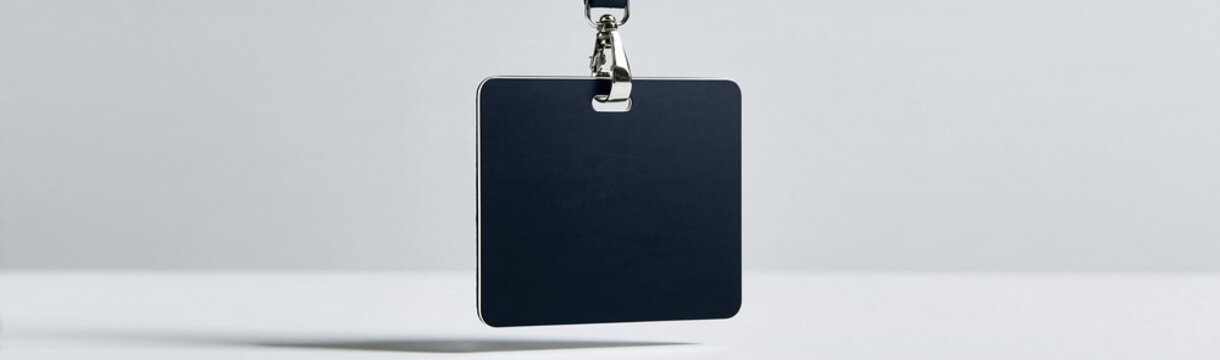 Blank Black Square Tag on Lanyard: A minimalist composition featuring a blank, square black tag hanging from a metallic clasp and lanyard against a soft, blurred backdrop.