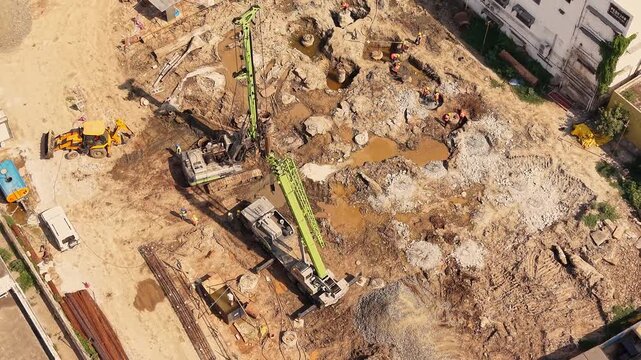 Land drilling machine and trucks excavating foundation at construction site development