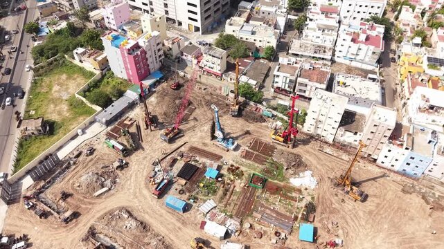 Piling rig and machinery at urban building construction site surrounded by city development