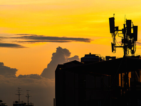 Silhouette of Cell Tower Antenna Array Against Dramatic Orange Sunset