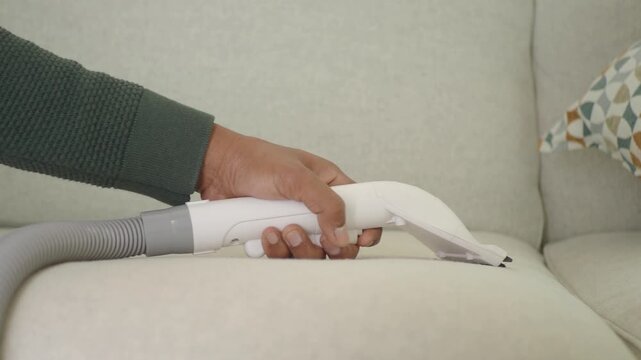 Cleaning a sofa with a vacuum attachment to remove dirt and dust