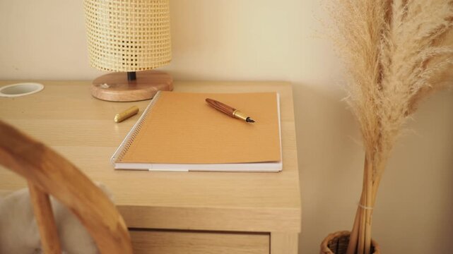 Desk with notebook and pen alongside a decorative plant in a room