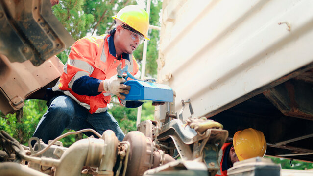 Professional mechanics inspecting engine and hydraulic system of heavy truck, commercial vehicle maintenance and repair service concept.