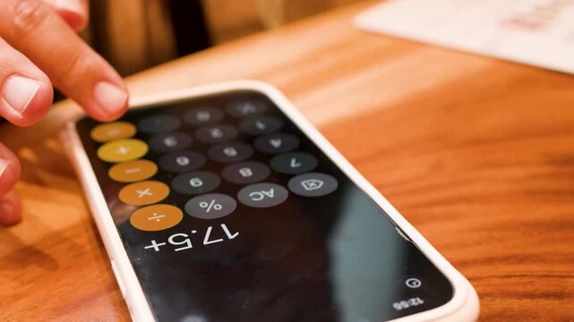Person Calculating Bill on Smartphone Screen at Restaurant Table