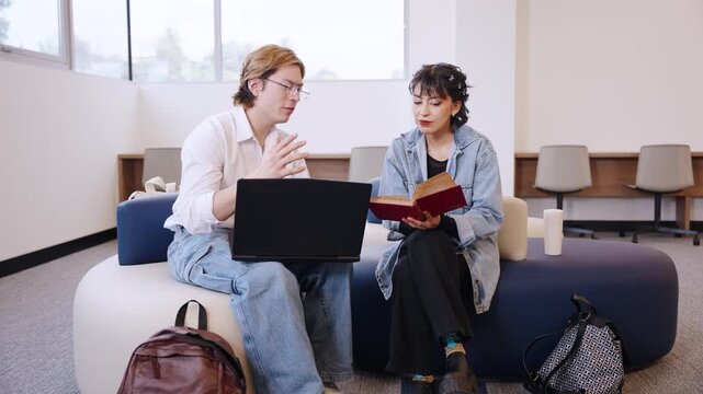 Latina university student discusses a textbook passage with a classmate using a laptop in a bright campus study lounge