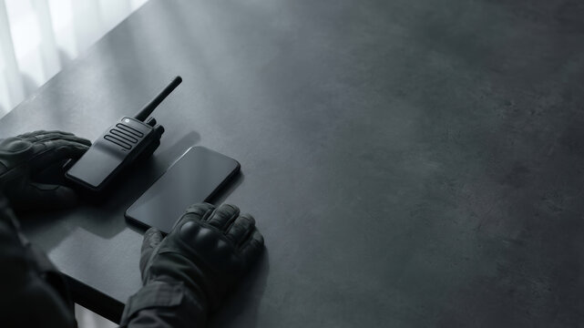 Walkie talkie security guard hand crisis management concept on dark desk with encrypted communication equipment and tense mood