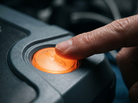 Close up of hand pressing orange round power button