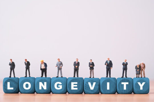 Longevity concept with people of different ages standing on wooden blocks representing healthy aging, longer life, workforce demographics, retirement planning and an aging population society.