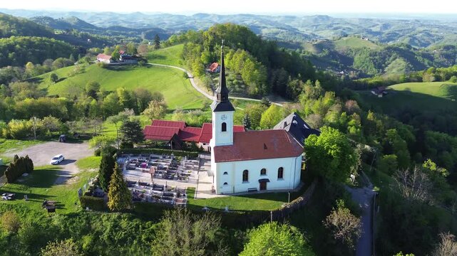 Aerial drone view of St. Urban's Church in &Scaron;ober near Maribor, Slovenia, surrounded by green hills, forests and rural countryside.