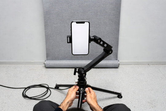 Person Setting Up Smartphone on Tripod Mount for Content Creation