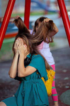 Mom Overwhelmed By Playful Kids Pulling Hair In The Park. Exhausted mother experiences high stress levels while young children playfully pull her long hair
