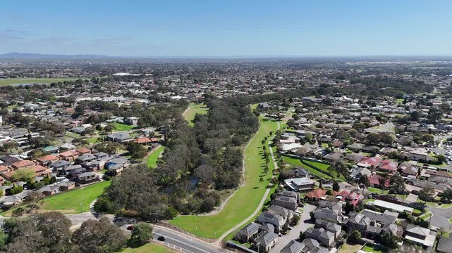 Aerial drone view of the Werribee River, walking trail and green parkland winding through residential neighborhoods and parklands in Werribee, Melbourne, Victoria, Australia.